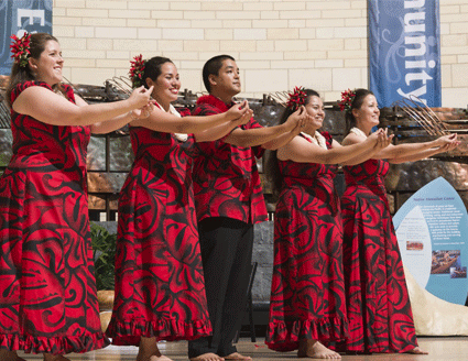 Hula dancers performing in matching red and black floral clothing.